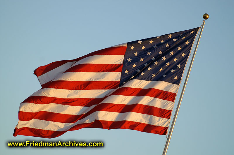 The American Flag, waving proudly against a blue sky at sunset.
